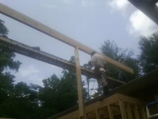 Carpenter setting a ridge beam over a new addition frame — Ice Dam Removal by Roofing Brothers in Kyle