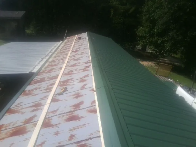 Old rusted panels beside newly installed green metal roofing — Wind Damage Roof Repair by Roofing Brothers in Kyle