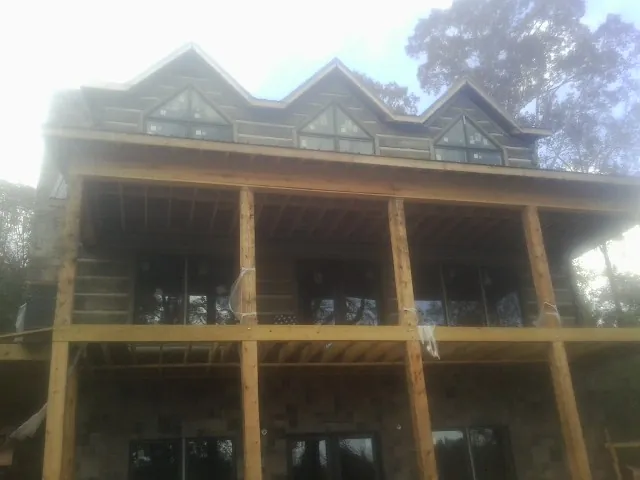 Dormers and porch framing on a large log home under construction — Roof Coating work by our crew in Kyle
