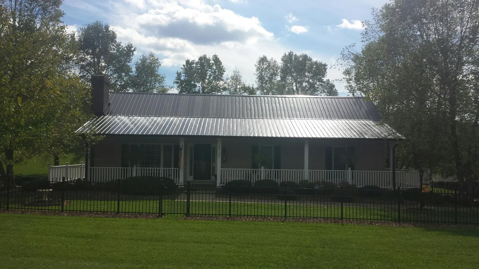 Gray metal roof on a brick ranch with a full width front porch — Gutter Guard Installation work by our crew in Kyle